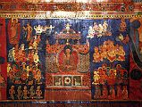 Tibet Guge 07 Tsaparang Red Temple 10 Band Life of Buddha � nowhere has it (the life of Buddha) been represented with so many details, with such a richness of scenes and with such a movement as here at Tsaparang. These frescoes have to be singled out as works of art. � Still above, the Buddha standing with the pindapatra in his right hand, indicates his resolution to deliver the famous first sermon. He starts walking towards Sarnath and en route meets the ajivaka Upagana, here represented with the ascetic stick: it is to him that he reveals his proposal to go to Banares to preach the law. The scene of preaching is, in fact, represented on the following panel. The Buddha sits on a throne covered by a rich canopy, with his hands in the attitude of the preaching mudra. On the basement of the throne are the traditional symbols of this culminating moment in the life of the Saint of the Sakyas namely, in the middle, the wheel representing, according to ancient symbolism, the first preaching; and on both sides two deer, reminding of the park actually called �the Deer Park�, where the famous ceremony was pronounced. Around him, in the act of devoted concentration and kneeling as a mark of homage, is a numerous crowd of every kind of creature: garuda above, nagas slightly below, gandharva and kinnaras, and then deities guided by Brahma and ascetics. The five emaciated yogins praying in the foreground possibly reproduce his first disciples. - Giuseppe Tucci: The Temples of Western Tibet and their Artistic Symbolism (1935). Photo - Weyer/Aschoff: Tsaparang, Tibets Grosses Geheimnis.